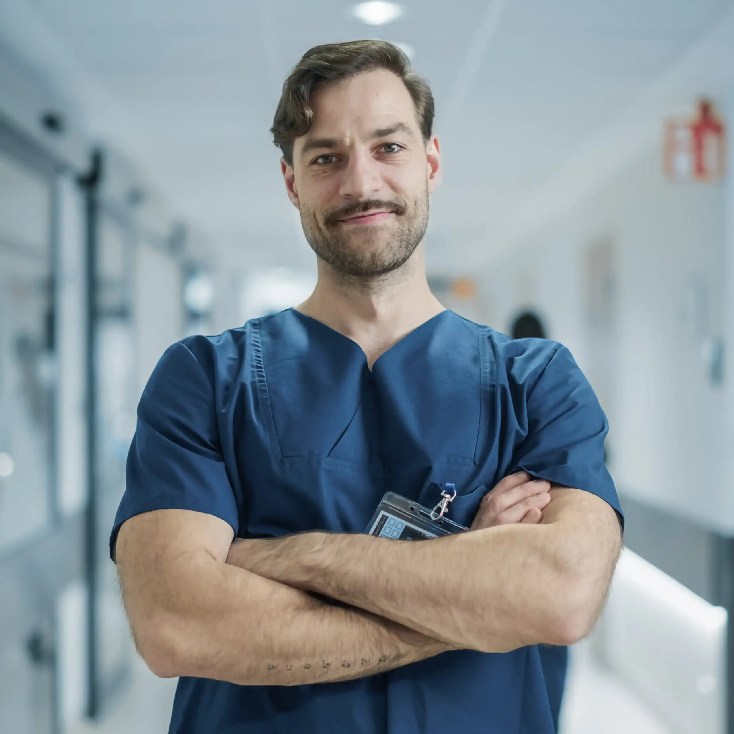 Un profesional sanitario joven de sexo masculino con los brazos cruzados