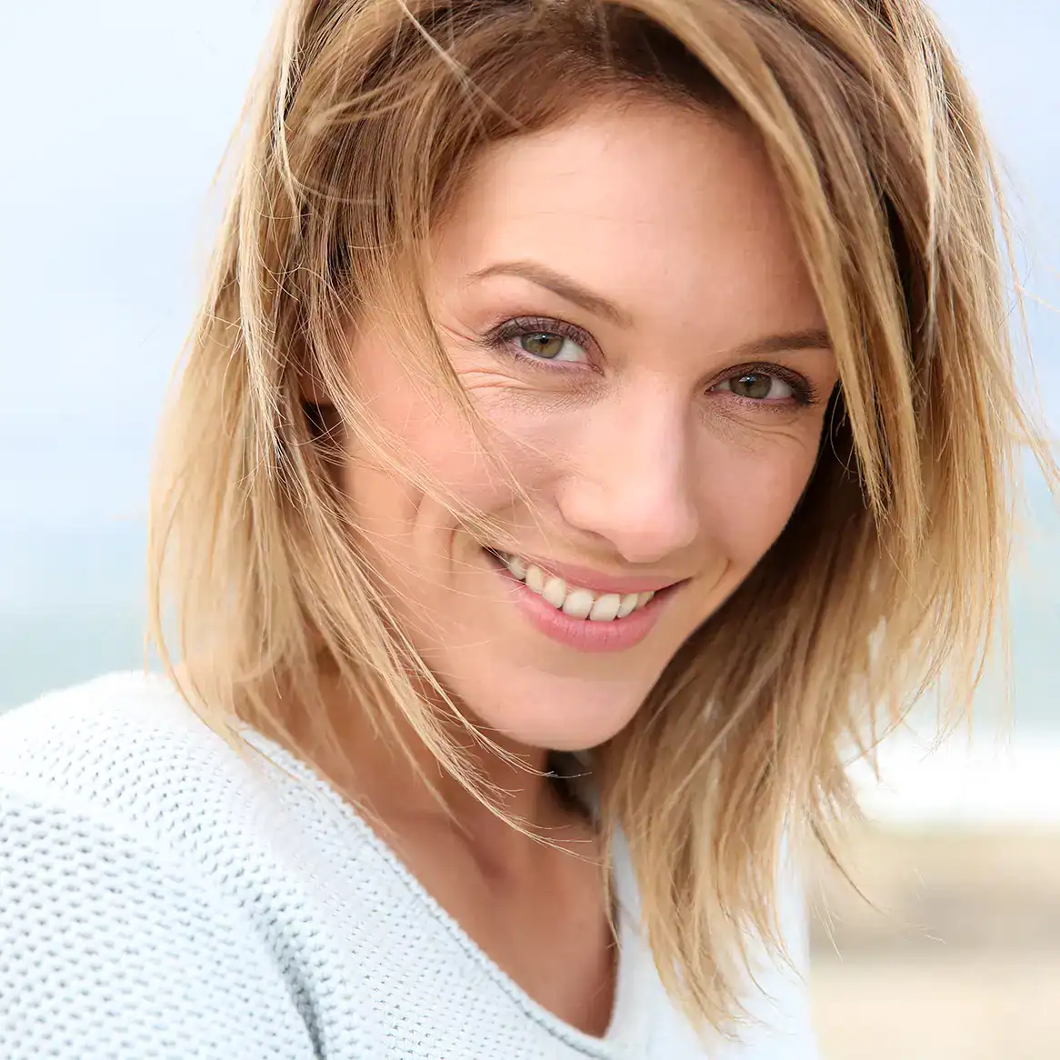 Beautiful middle aged woman smiles while walking on the beach