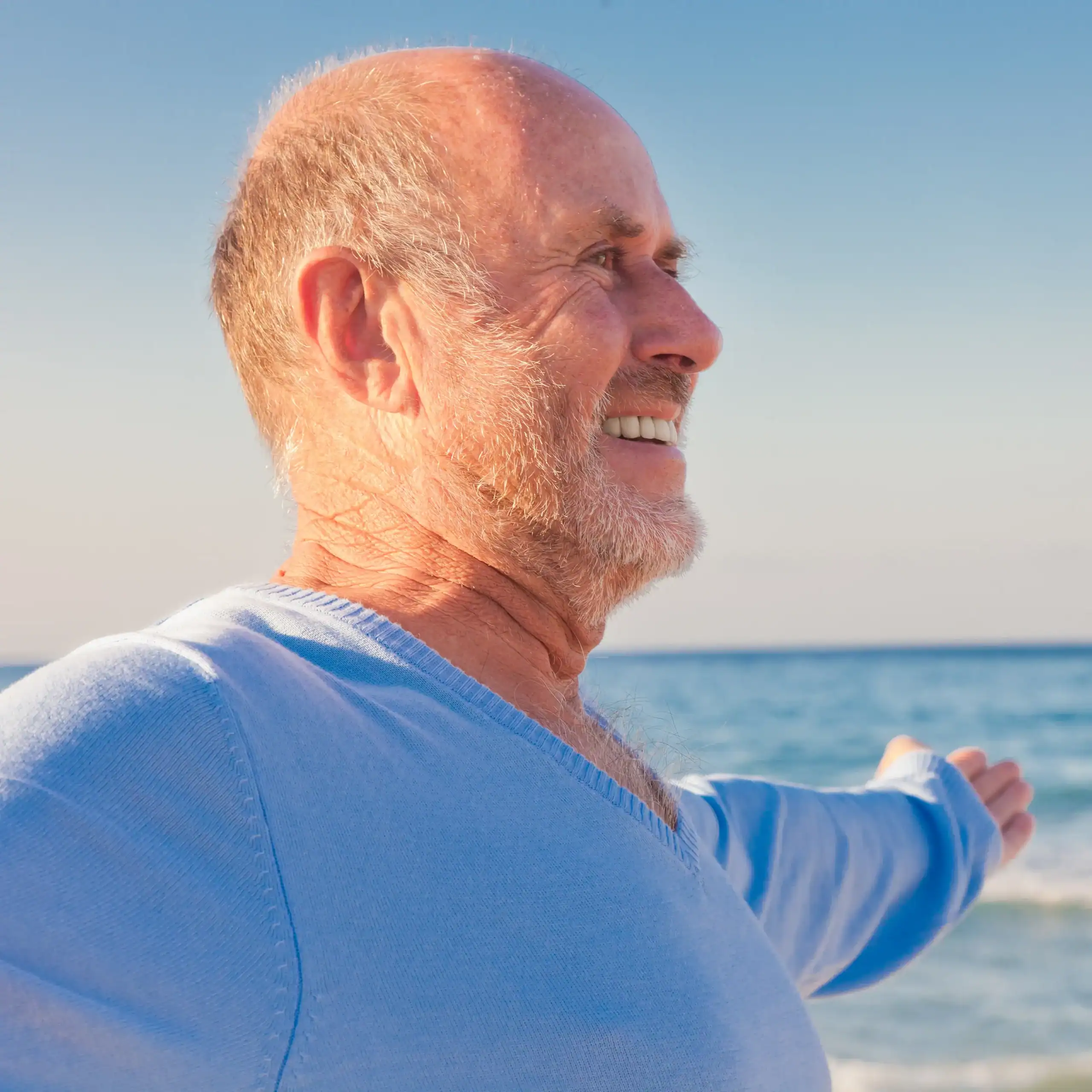 Older white man with blue sweater on the beach