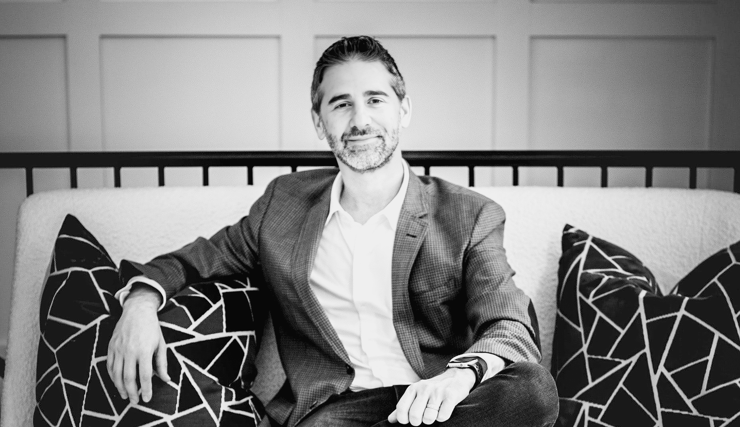 El Dr. Marcus Goodman, fundador de Goodman Dermatology, está sentado en un sofá