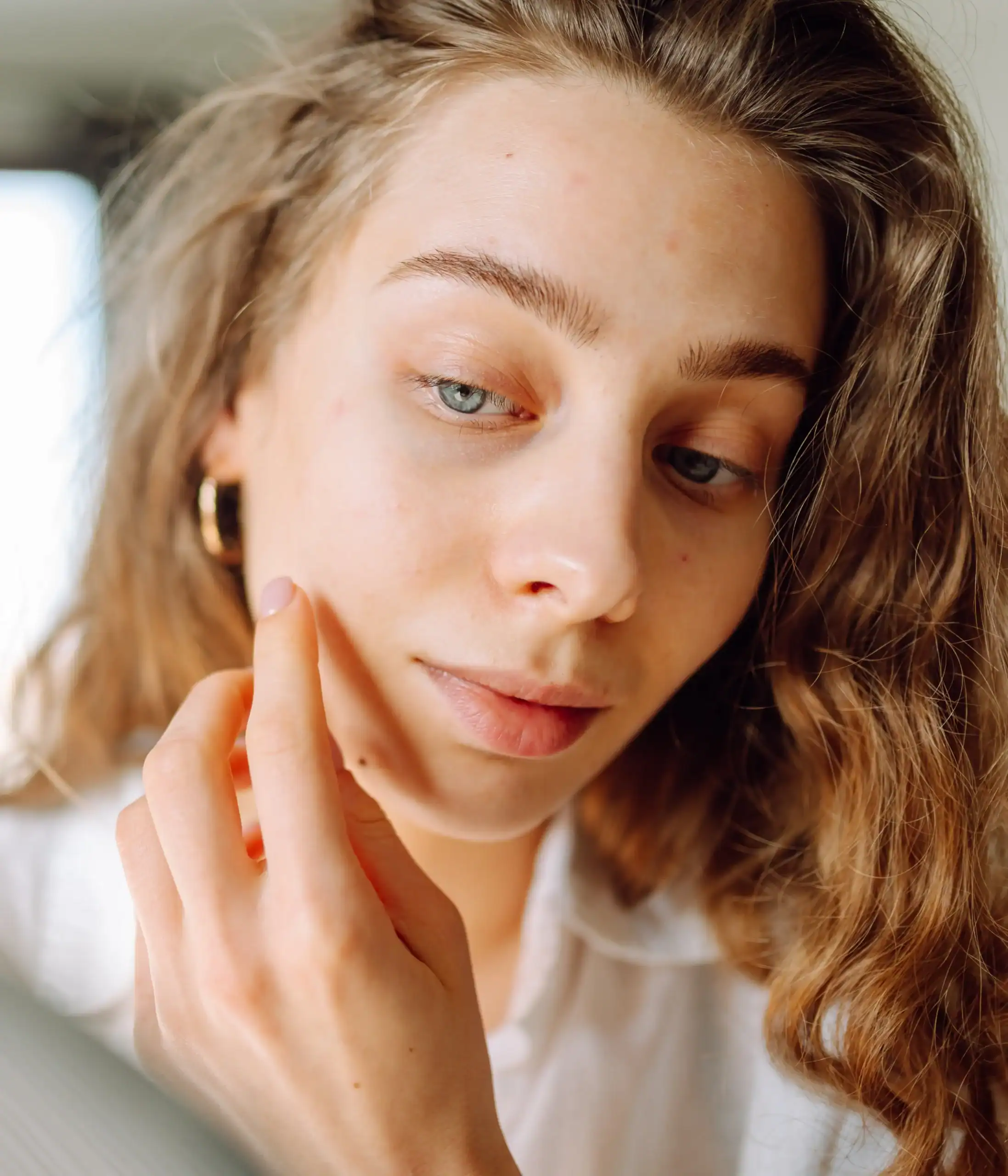woman looks at her skin quality in a mirror